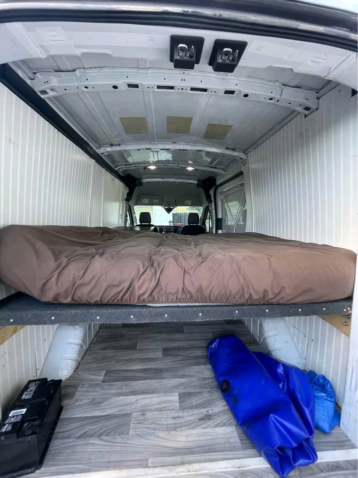 Full-size bed sleeping area inside 2016 Ram ProMaster campervan
