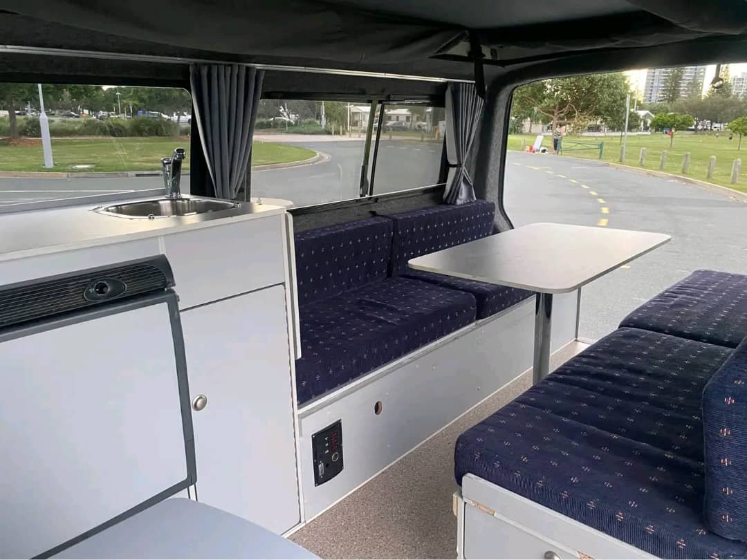 Large dining table bed conversion inside campervan