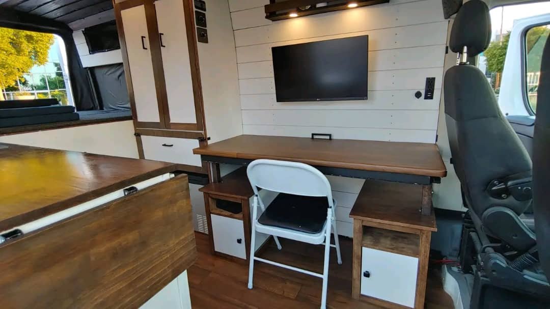 Seating, entertainment, and workspace area inside ProMaster campervan